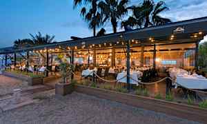 En restaurant ved stranden med hvite duker på kveldstid. (AI-generert tekst)