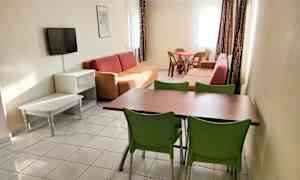 Et oppholdsrom med sofaer, et spisebord med stoler og en veggmontert TV. (AI-generert tekst)