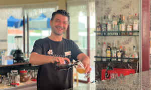 En bartender heller opp en drink ved en bar. (AI-generert tekst)