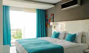 Moderne hotellrom med en dobbeltseng, hvite og turkise farger. (AI-generert tekst)