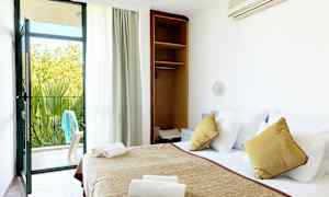 Et hotellrom med en oppredd seng, åpen skap og en balkongdør som fører ut til en uteplass. (AI-generert tekst)