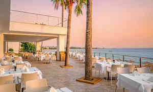 Utendørs restaurant med havutsikt ved solnedgangen. (AI-generert tekst)