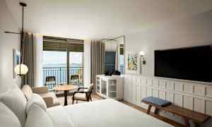 Hotellrom med havutsikt gjennom en balkongdør. (AI-generert tekst)