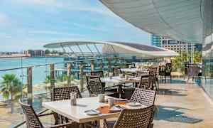 Utendørs servering med dekkede bord og havutsikt. (AI-generert tekst)