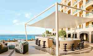 En utendørs bar med sitteområde, parasoll og utsikt over havet. (AI-generert tekst)