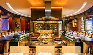 Interiør av en restaurant med åpen kjøksløsning og sitteplasser rundt. (AI-generert tekst)