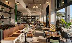 Moderne innredet restaurant med store vinduer og sitteplasser. (AI-generert tekst)