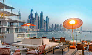 Et moderne uteområde med komfortable sitteplasser og utsikt over en bysilhouett ved vannet. (AI-generert tekst)