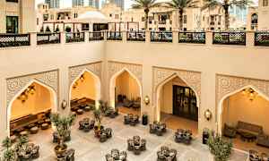 Velutformet gårdsplass med sittegrupper, pynteorientalske buer og belysning, omgitt av moderne og tradisjonell arkitektur. (AI-generert tekst)