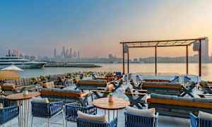 Utendørs loungeområde med utsikt over vannet og bysilhuetten. (AI-generert tekst)