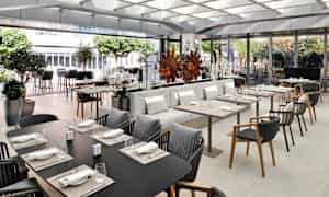 En elegant restaurant med bord og sitteplasser, dekorert med planter og moderne innredning. (AI-generert tekst)