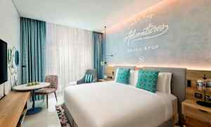 Et moderne hotellrom med en stor seng, dekorative puter, en sittegruppe og et skrivebord. (AI-generert tekst)