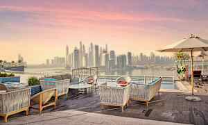 Terrasse med sitteplasser og utsikt over en bysilhuett ved solnedgang. (AI-generert tekst)