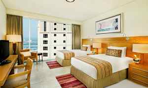 Hotellrom med to enkeltsenger, skrivebord og store vinduer. (AI-generert tekst)