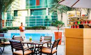 Et kafébord med to drikker og en bakervare ved et basseng, omgitt av trær og en glassvegg. (AI-generert tekst)