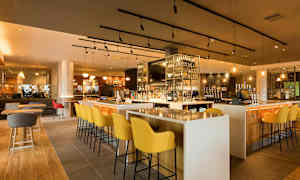 En bar med moderne møbler og en godt fylt hylle med flasker. (AI-generert tekst)