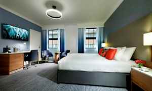 Et hotellrom med en stor seng, skrivebord og sittemøbler. (AI-generert tekst)