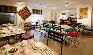 En kafé med dekkede bord og stoler med fargerike puter. (AI-generert tekst)