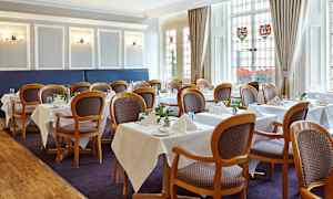 Innendørsbilde av en spisesal med oppstilte bord og stoler. (AI-generert tekst)