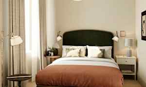 Et hotellrom med en dobbeltseng, to nattbord og dekorative detaljer. (AI-generert tekst)