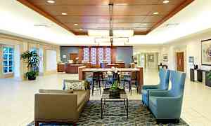 Hotellobby med sittegrupper, bord, planter og resepsjonsdisk. (AI-generert tekst)