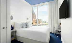 Bilde av et hotellrom med en komfortabel dobbeltseng, et stort vindu og moderne innredning. (AI-generert tekst)