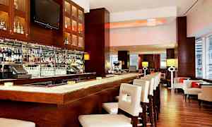 Interiør av en elegant bar med en velutstyrt bardisk og hvite barstoler. (AI-generert tekst)