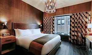 Et hotellrom med en stor seng, nattbord, vindu med gardiner og et skrivebord ved siden av. (AI-generert tekst)