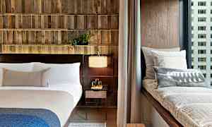 Et moderne soverom med en seng, en vindusbenk med puter og en nattbordslampe. (AI-generert tekst)