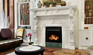 En elegant stue med en hvit, utsmykket peis og bøker på hyllene ved siden av. (AI-generert tekst)