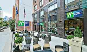 En uteterrasse foran et hotell med sittegrupper og dekorasjoner av planter. (AI-generert tekst)