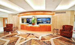 En lobbyinnredning med en resepsjonsdisk, sitteområder og et marmorgulv. (AI-generert tekst)