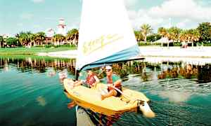 En seilbåt på en innsjø med en strand og grønne trær i bakgrunnen. (AI-generert tekst)