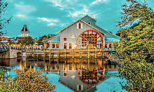 Bygning med et stort hjul ved vann, omgitt av trær og vegetasjon. (AI-generert tekst)