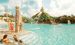 Bildet viser et utendørs basseng med mennesker som nyter vannet og en pyramideformet vannattraksjon i bakgrunnen. (AI-generert tekst)