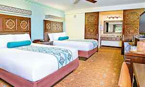 To veloppredde senger i et hotellrom med lyse vegger og dekorative detaljer. (AI-generert tekst)