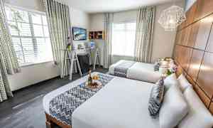 Et hotellrom med to dobbeltsenger, elegant interiør og dekorative detaljer. (AI-generert tekst)