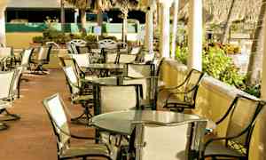 Utendørsområde med bord og stoler for sitteplasser, omgitt av vegetasjon. (AI-generert tekst)