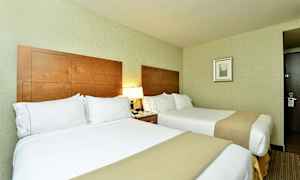 Hotellrom med to senger, trepanel som hodegavl og lamper på nattbord. (AI-generert tekst)