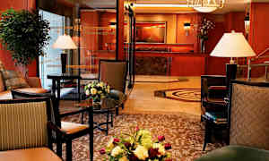 Et smakfullt innredet hotellobbyområde med møblert sitteplasser, interiørdetaljer, blomsterarrangementer og resepsjonen i bakgrunnen. (AI-generert tekst)