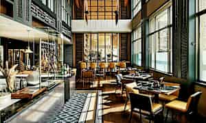 Interiør av en moderne restaurant med bord og stoler, store vinduer og et åpent kjøkkenområde. (AI-generert tekst)