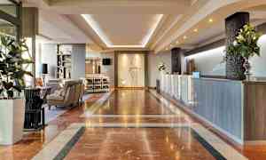 Hotellobby med marmorgulv, resepsjon og sittegruppe. (AI-generert tekst)