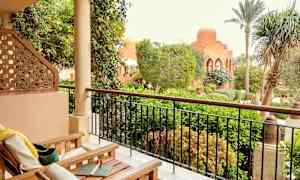 Et uterom med møbler foran en frodig hage og en bygning med kuppel. (AI-generert tekst)