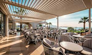 En terrasse med sitteplasser, utsikt over kysten. (AI-generert tekst)