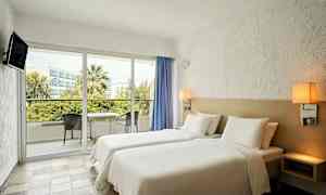 Hotellrom med to enkeltsenger og en balkong med møbler. (AI-generert tekst)