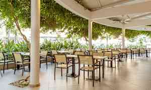 Bilde av en uteservering med bord og stoler under tak. (AI-generert tekst)