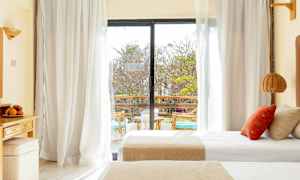 Et hotellrom med dobbeltsenger og en glassdør som fører ut til en balkong. (AI-generert tekst)