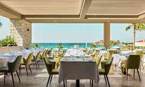 Restaurant med dekkede bord og utsikt mot havet. (AI-generert tekst)