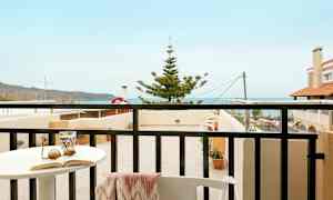 En balkong med utsikt mot havet og nærliggende bygninger. (AI-generert tekst)