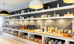 Frokostbuffé med brød, frokostblandinger, pålegg og drikkevarer. Hyller med porselen over. (AI-generert tekst)